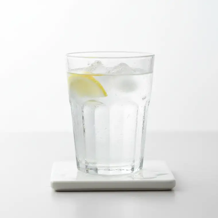 Młoda osoba z lekko spoconymi dłońmi trzyma szklankę z alkoholem, obraz ilustruje związek picia alkoholu z poceniem rąk i stóp